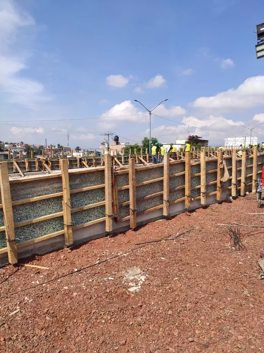 Muro perimetral cimbrado con tabla plástica y cuadrilla trabajando — cimbra plástica para construcción