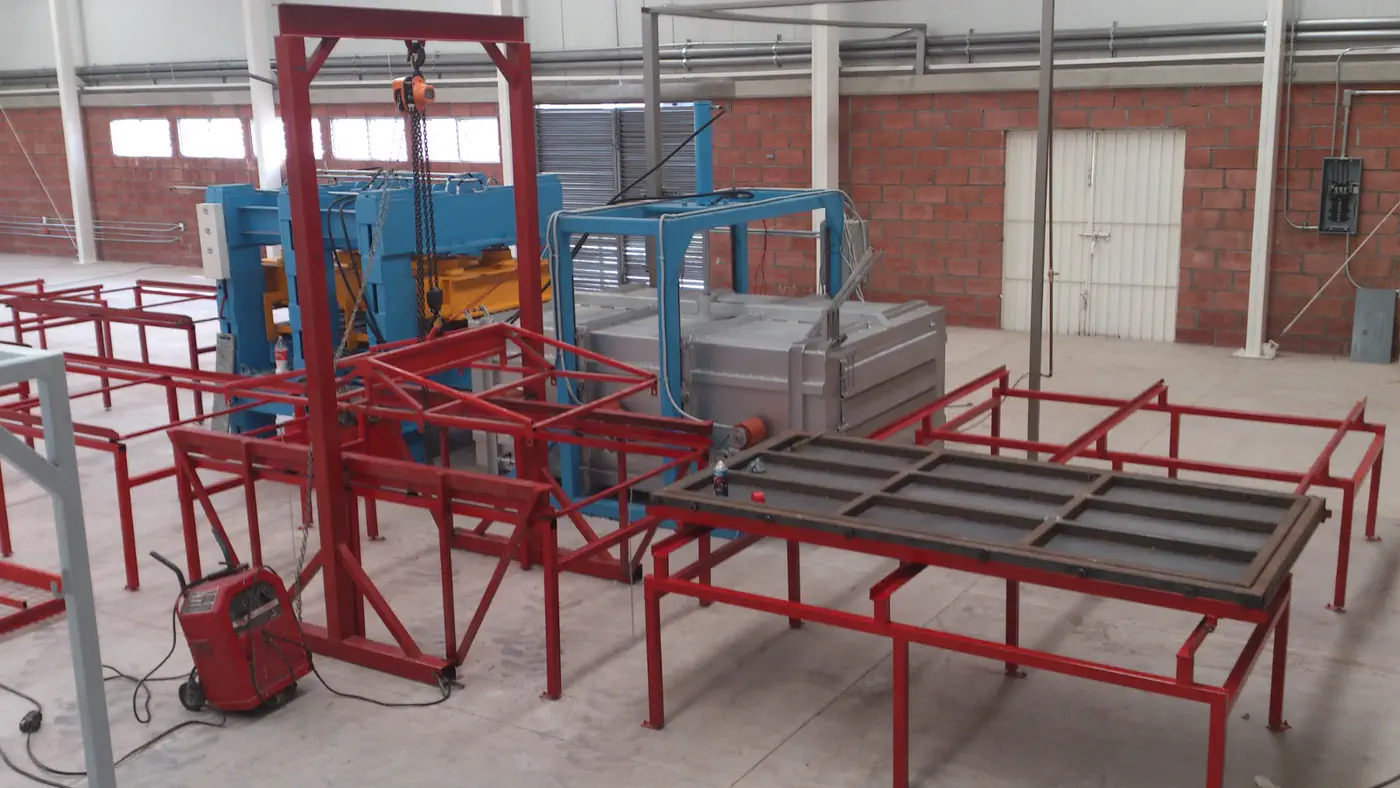 Línea completa de producción de tabla de plástico reciclado instalada en nave industrial, con prensa hidráulica, horno y mesas de enfriamiento
