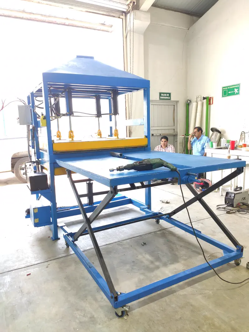 Prensa con mesa de tijera extendida para recibir la tabla de plástico recién prensada